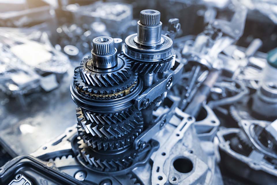 Closeup disassembled car automatic transmission gear part on workbench at garage or repair factory station for fix service or maintenance. Vehicle part detail. Complex industrial mechanism background